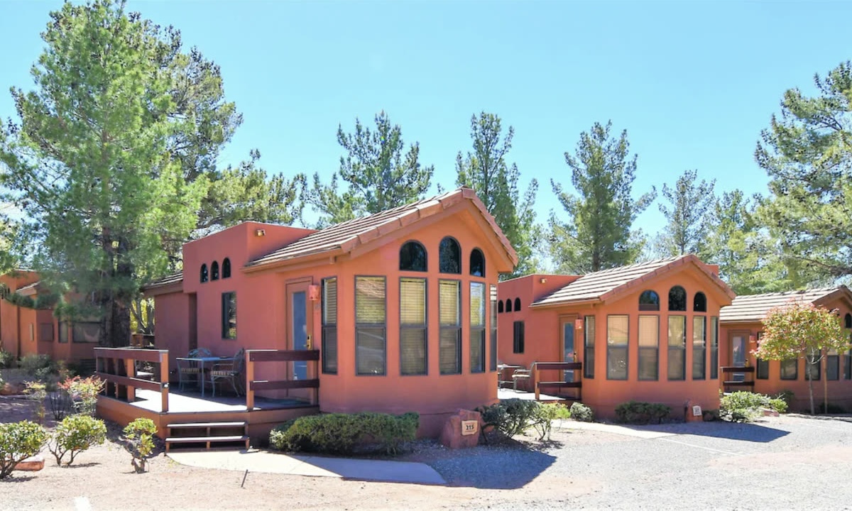A row of terracotta cottages at Sedona Pines Resort, each with its own deck, under tall pines